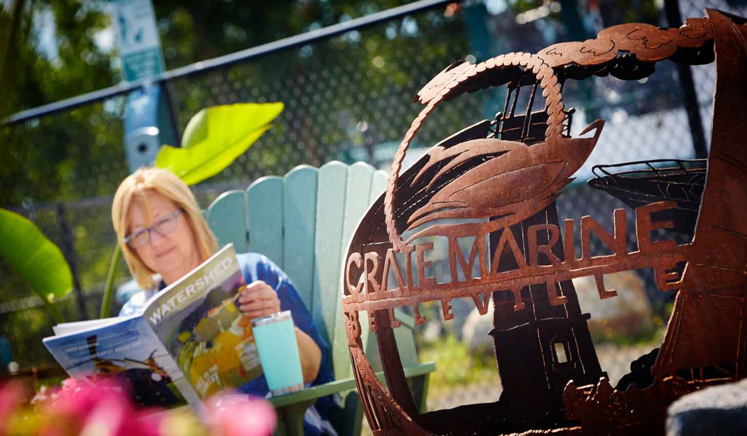 orb with crate marine’s logo close up with unfocused depiction of a woman reading a book in the background