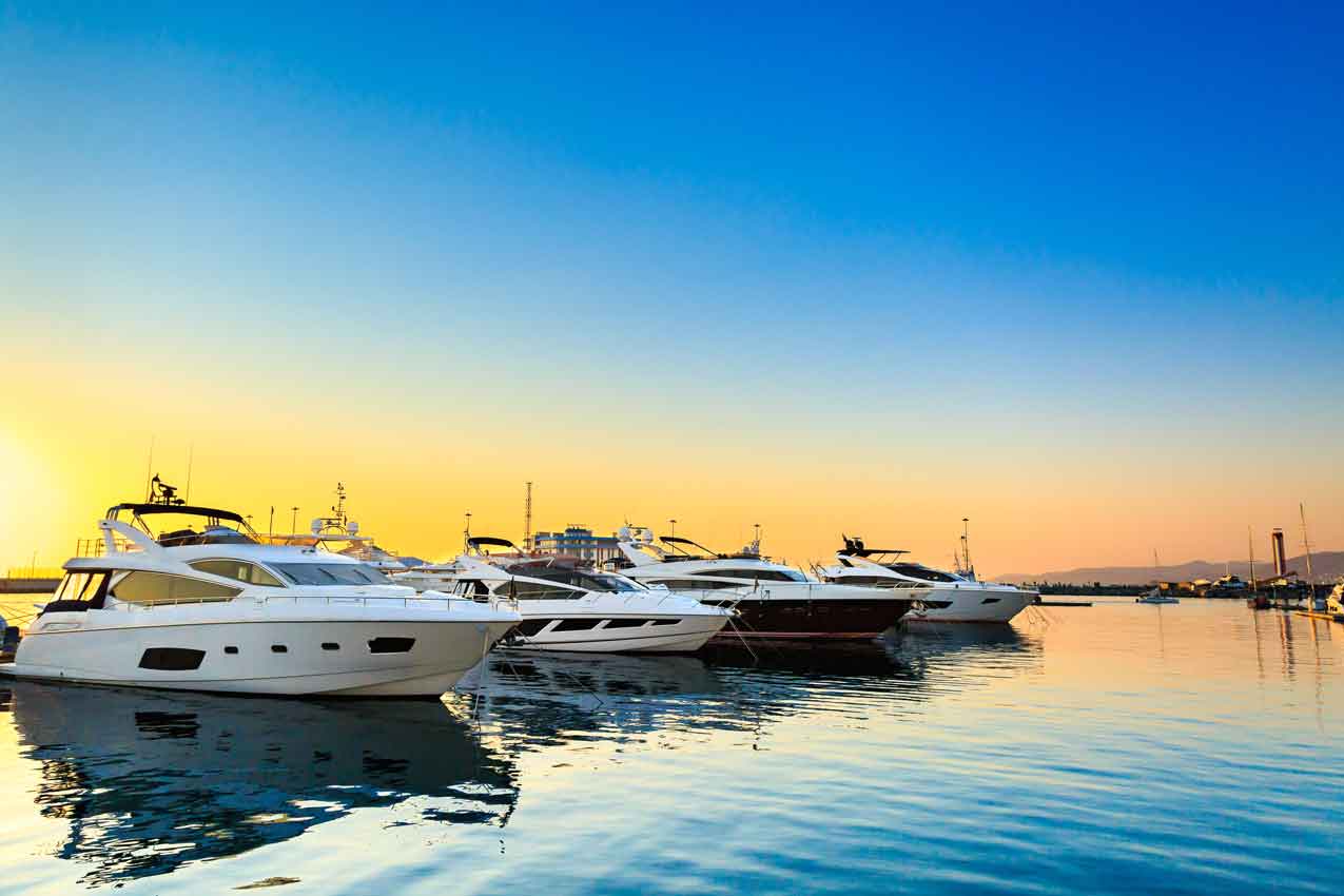 Luxury yachts docked in sea port at sunset