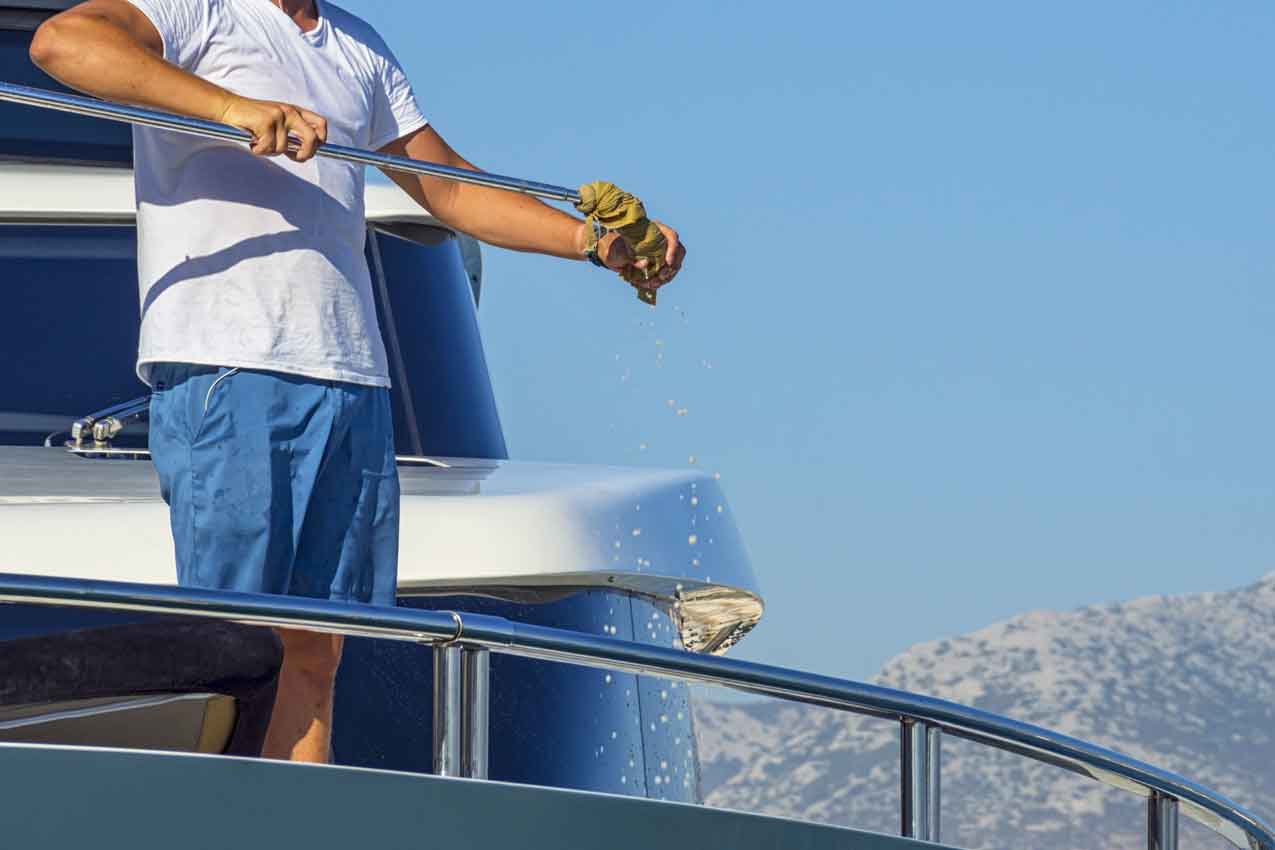 aceless boating crew member cleaning a boat part while docking, close up