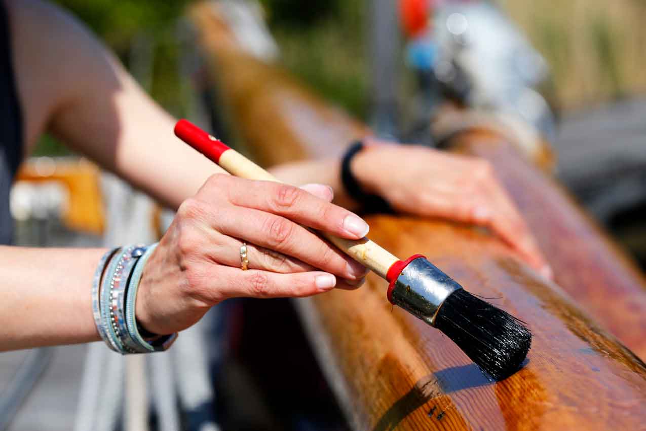 Varnishing the wooden mast of a classic sailing yacht