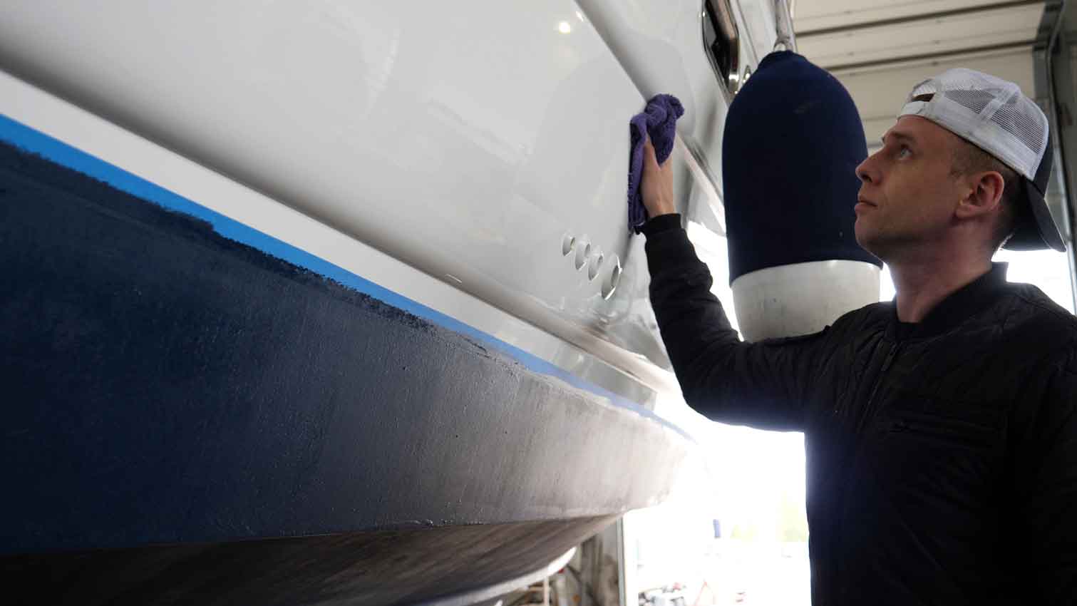 Professional male marina worker polishing a boat in storage