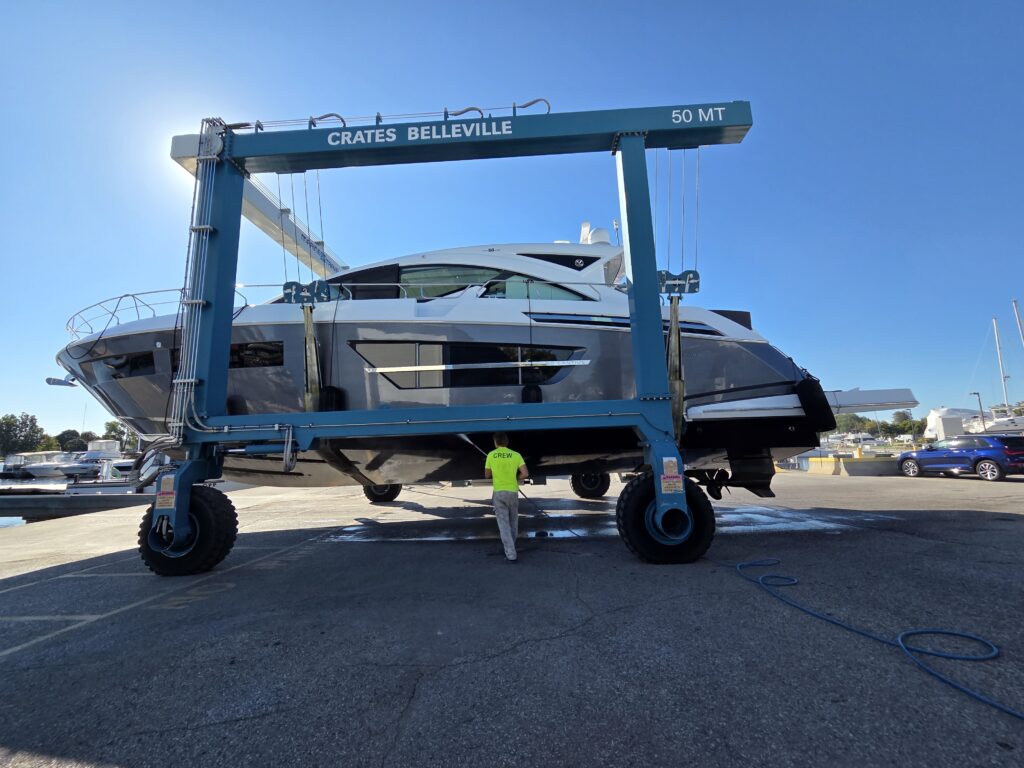 Crate Marine Belleville 50-ton travel lift hauling out a cruiser while crew pressure-washes the hull