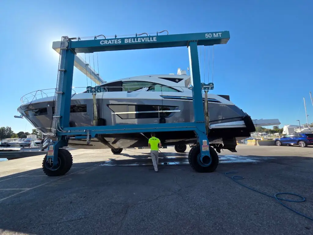 Crate Marine Belleville 50-ton travel lift hauling out a cruiser while crew pressure-washes the hull