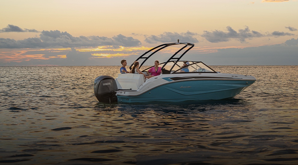 Hurricane SunDeck deck boat cruising at sunset